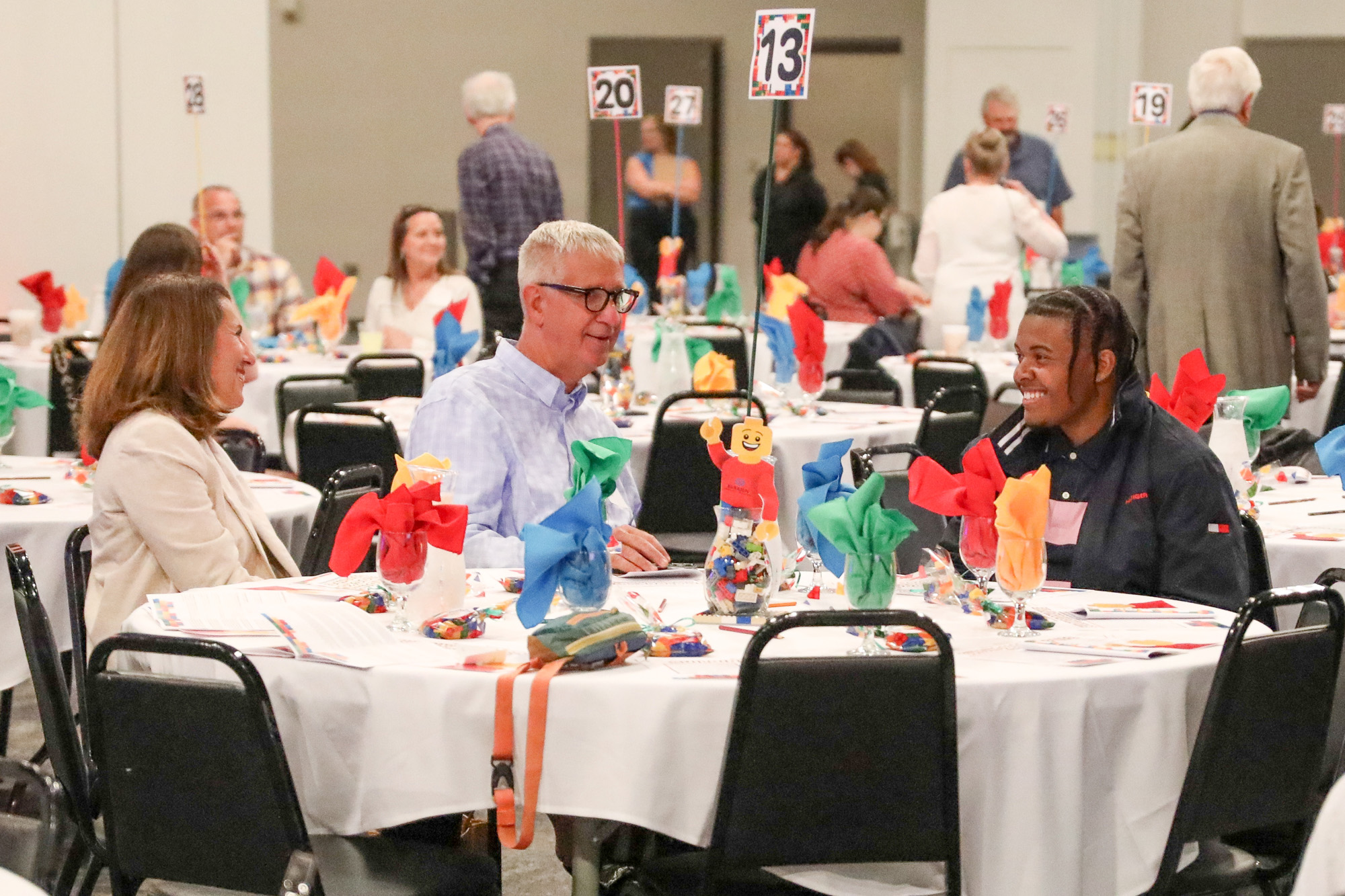 A photo showing three people sitting at a table talking - a student scholar and two donors.