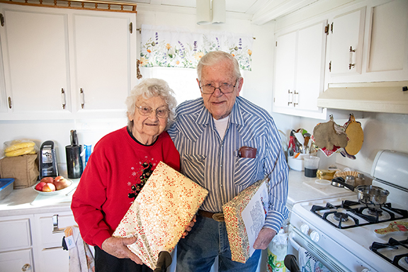 A man and woman standing side-by-side showing two Senior Care Kits.