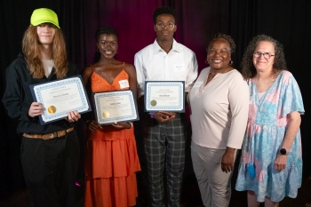 A teenager holding a certificate while standing next to an adult. 