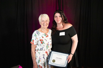 Two young women standing next to each other, both holding certificates. 