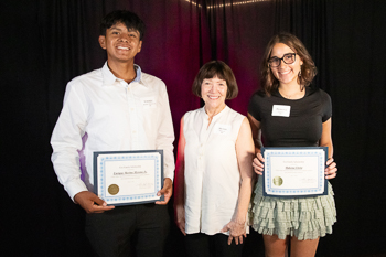 Two teens standing next to each other, both holding certificates. 