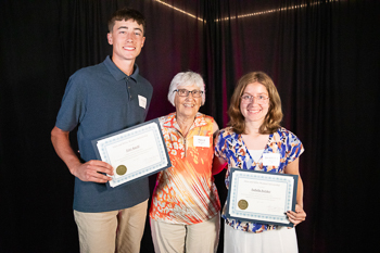A teenager holding a certificate while standing next to an adult. 