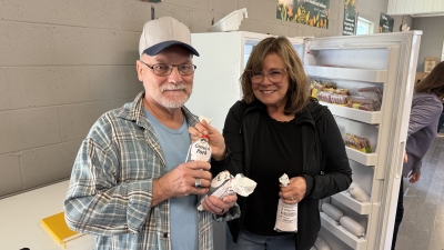 Two people standing next to each other holding bags of ground pork.