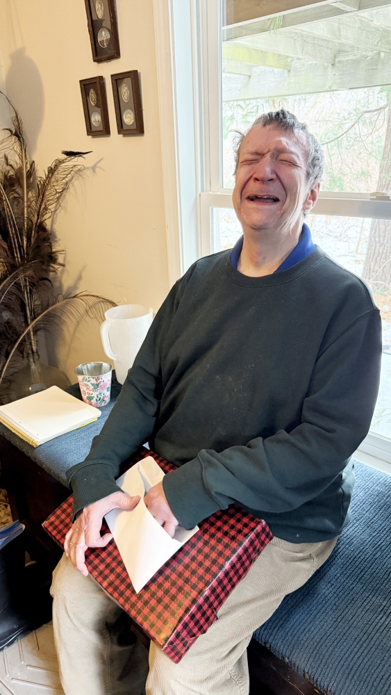 man sitting on bench holding box.