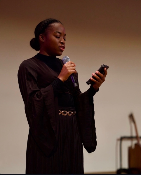 Denalia speaks into a microphone while reading from her phone.