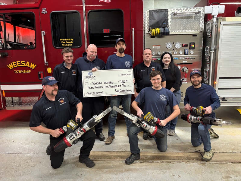 Group photo of firefighters in casual clothes holding equipment next to a large check from BCF.