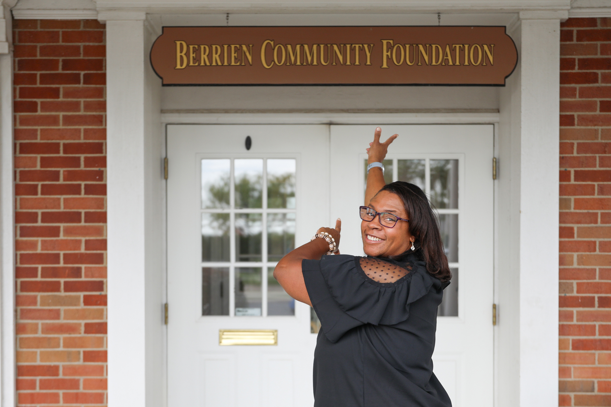 Nicole Grant pointing to the Berrien Community Foundation sign behind her. 