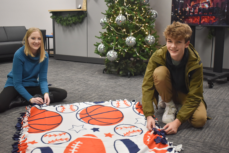 Two TEAM members smile for the camera while making no-sew blankets.