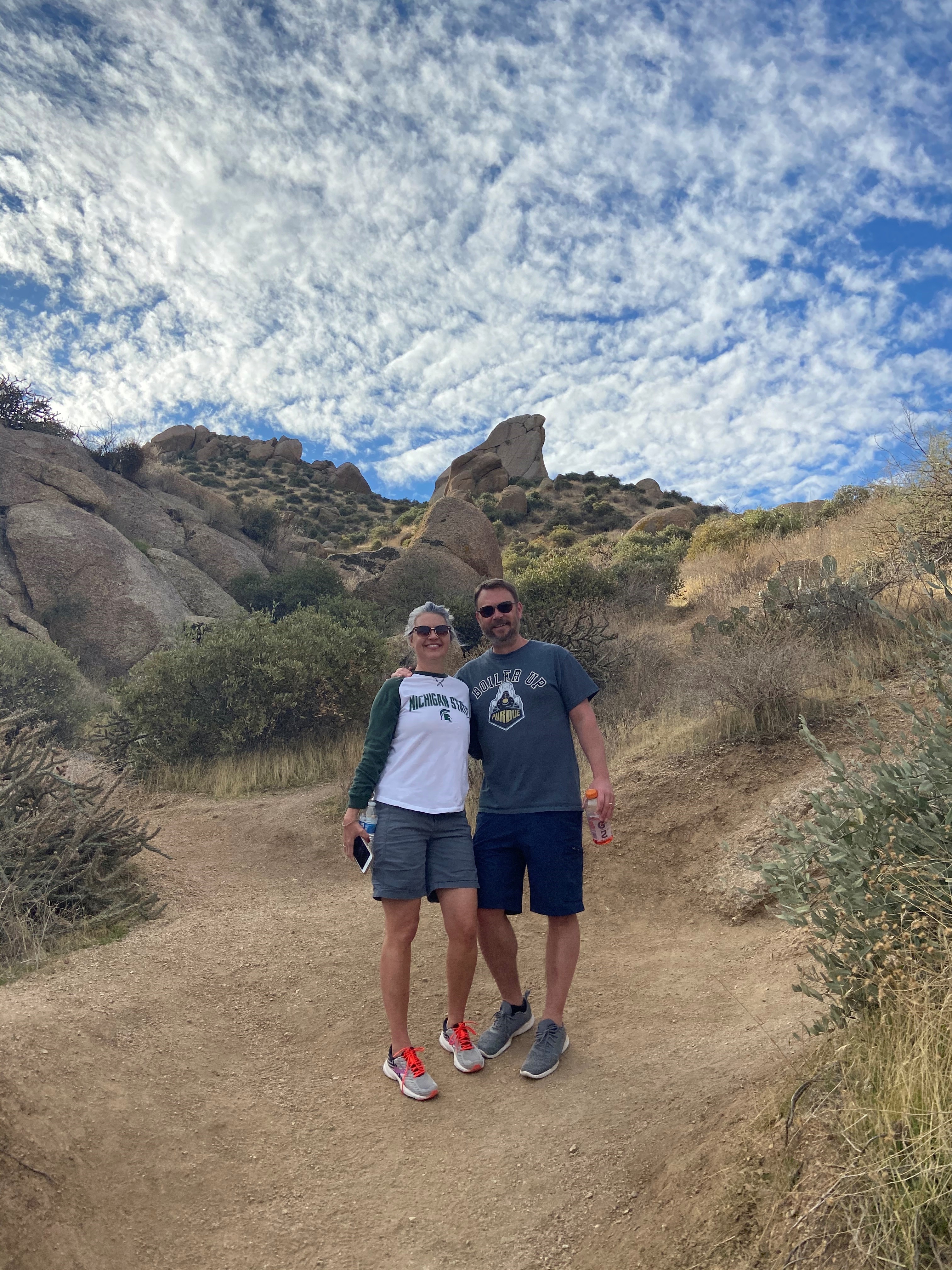 Man and woman standing in desert wearing hiking clothes.