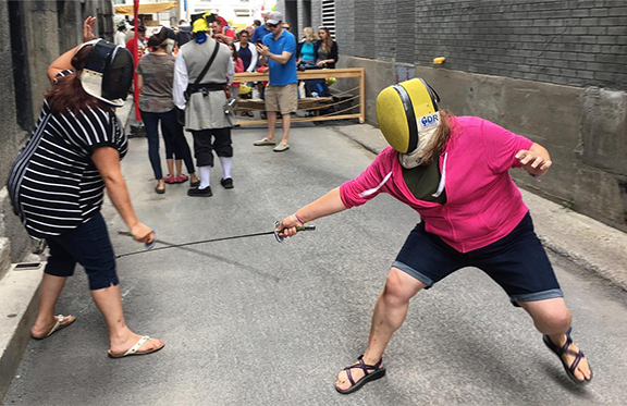 Two people fencing in an alley.