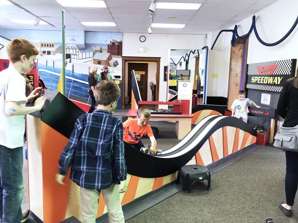 kids play on an indoor track with wooden vehicles