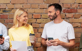 Photo of four people with phones, tablets or coffee in hand.