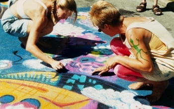 Judy Jones and Nicole Moon create chalk art on pavement.