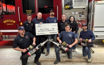 Group photo of firefighters in casual clothes holding equipment next to a large check from BCF.
