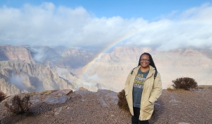 Elizabeth standing in front of a canyon and rainbow overhead.